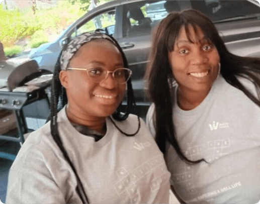 Two women standing in front of a car