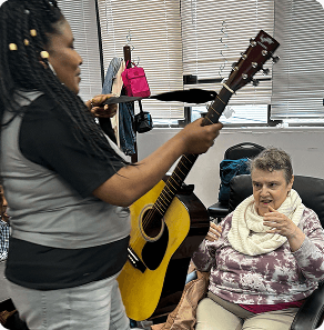 A woman handing a guitar to another woman