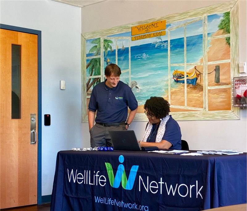 A man and woman working at a table during the WellLife Network Job Fair